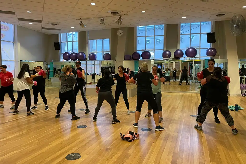 A member striking focus pads held by her partner during a Boxing class