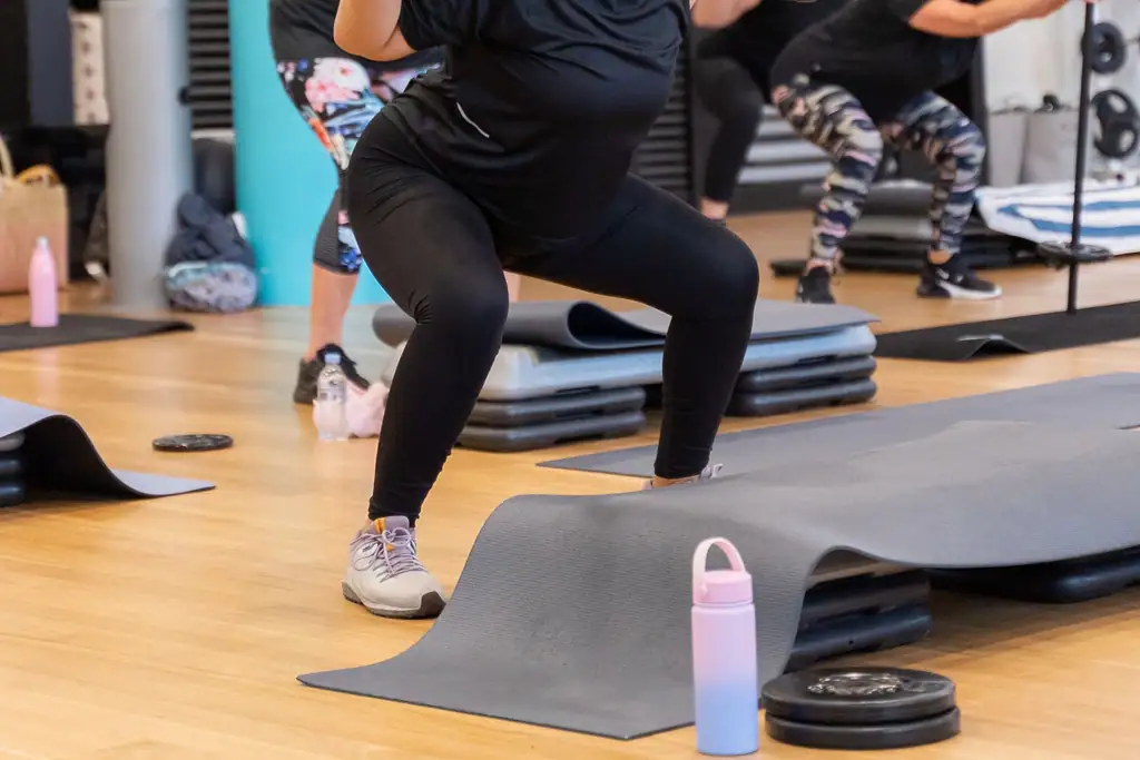A member loading plates onto a barbell before a Les Mills Body Pump class