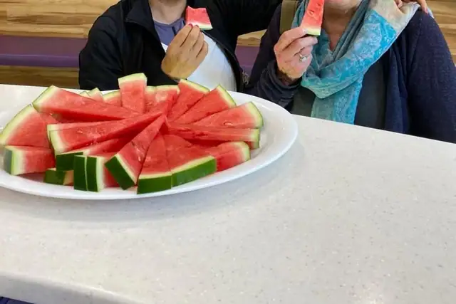Two members sharing a platter of watermelon at the front desk