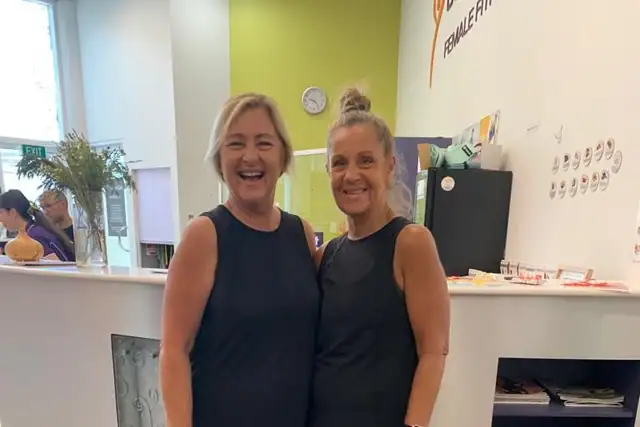 Two members standing together by the reception desk before a session