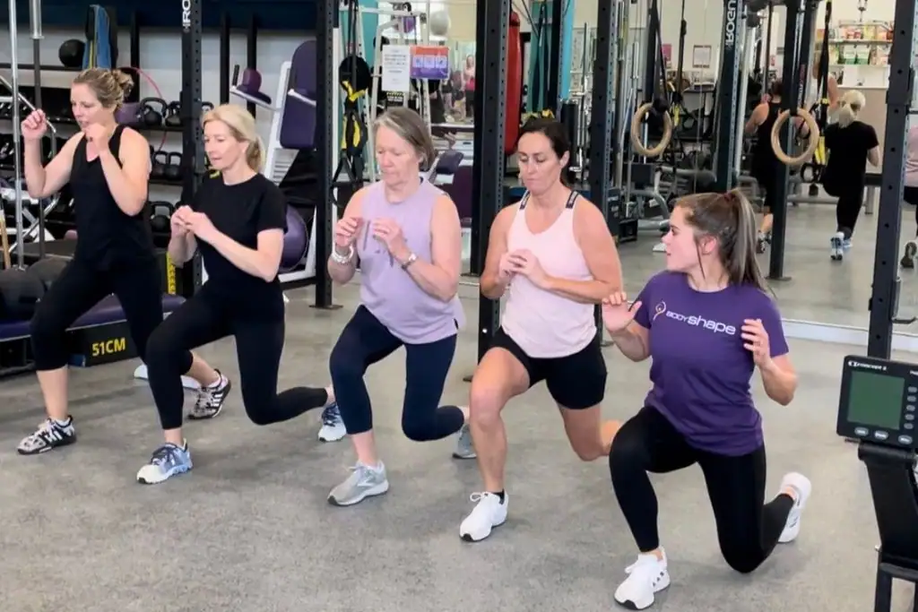 A line of members performing walking lunges led by their trainer