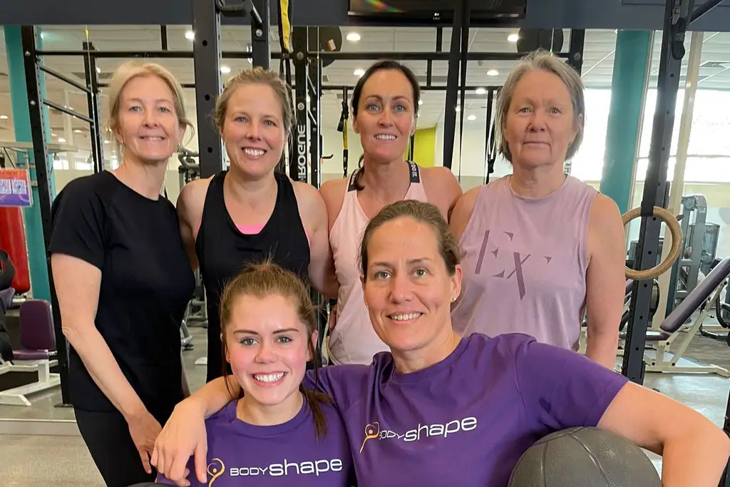 Six women holding medicine balls after a small group session