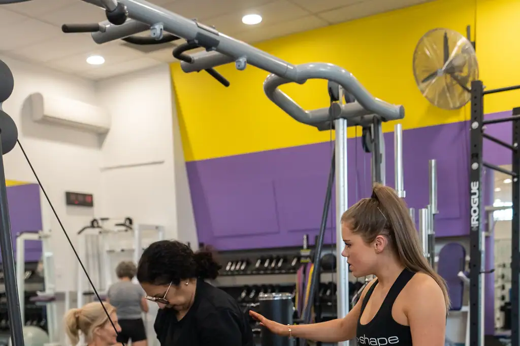A trainer coaching a small group through cable work on the gym floor