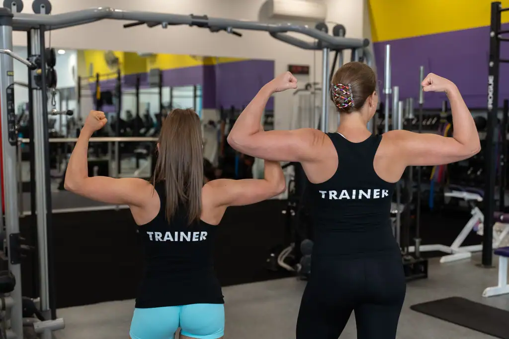 Two trainers in Body Shape shirts flexing beside the functional training rig